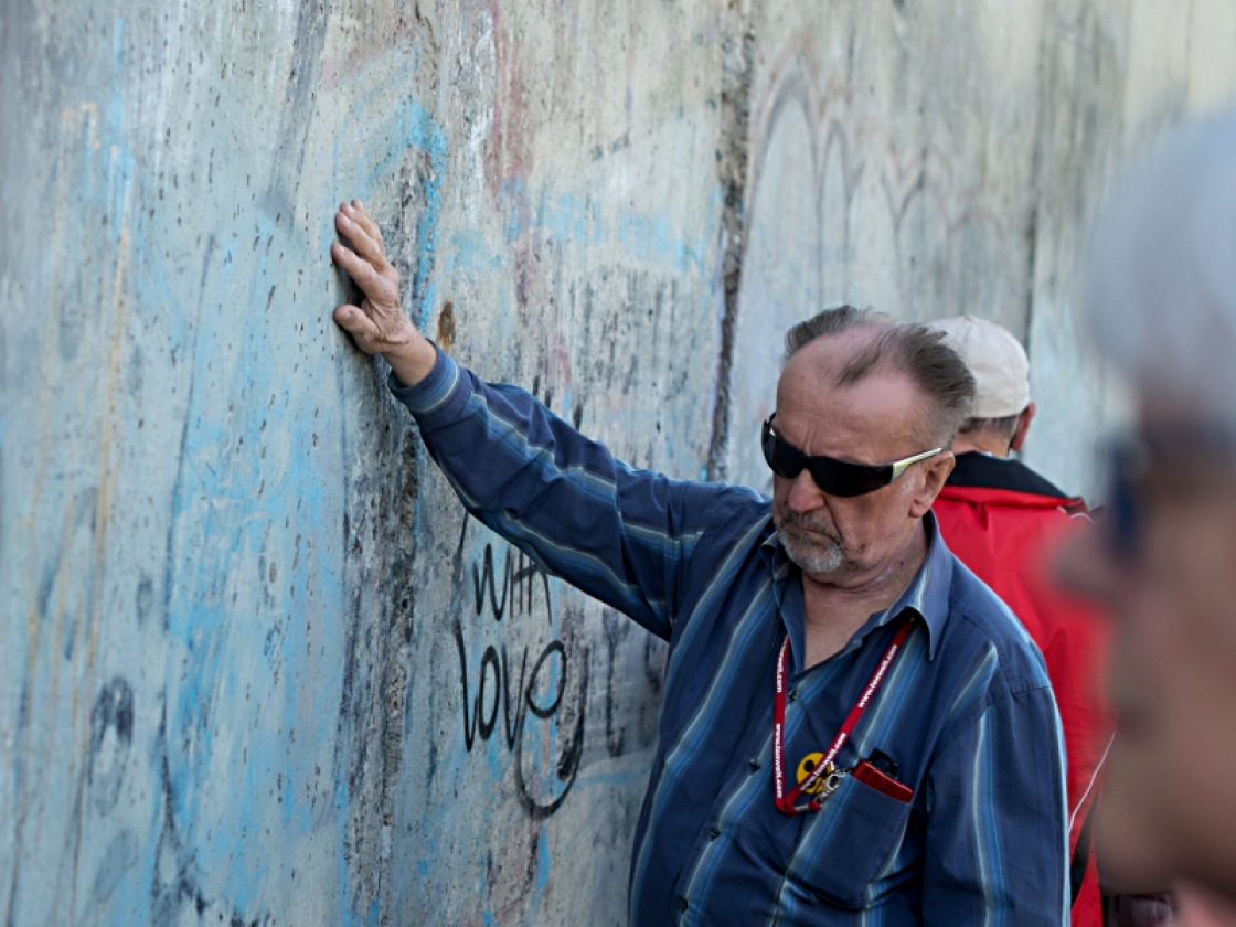 Besucher betatstet die Berliner Mauer