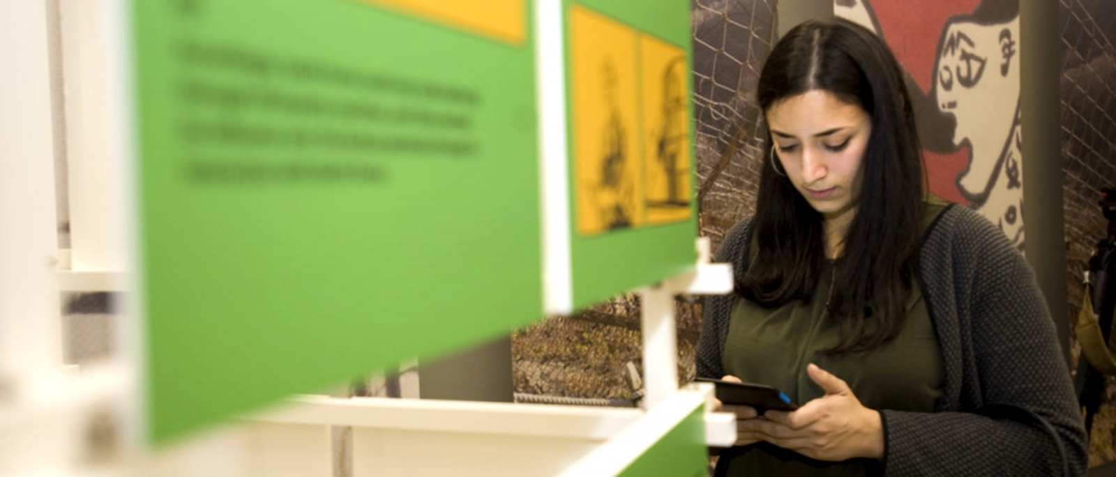 Eine junge Frau bedient ihr Smartphone in einer Ausstellung