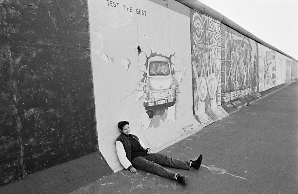 Person sits in front of the East Side Gallery